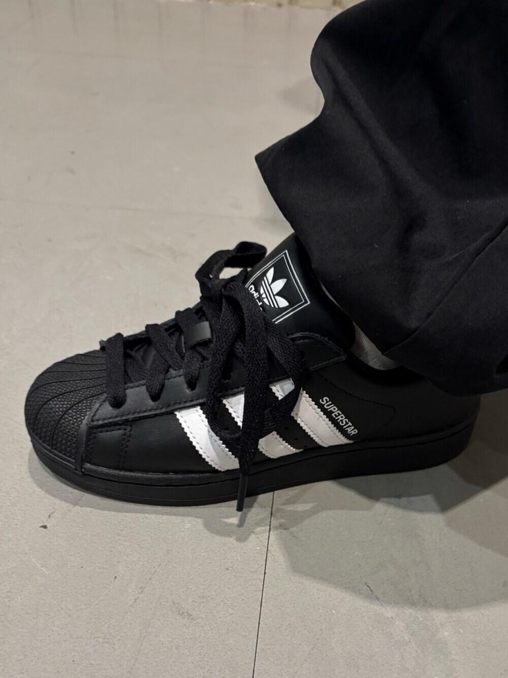 グレー系のジャージ、ブラック系のショルダーバッグ、ブラック系のスニーカーを着用したレディースの春コーディネートの4枚目の写真