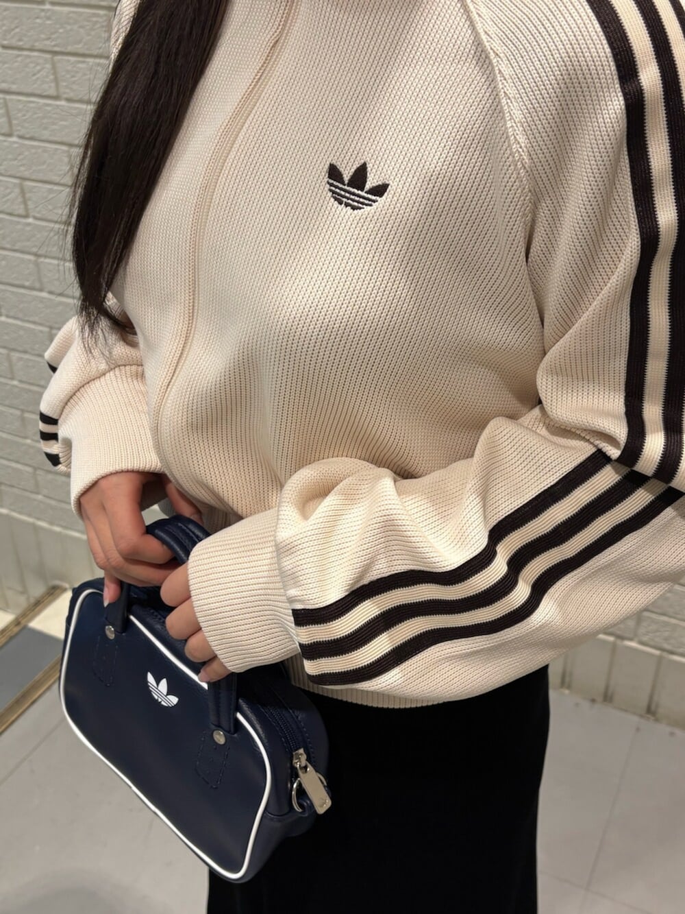 ホワイト系のジャージ、ブルー系のショルダーバッグを着用したレディースの冬コーディネートの3枚目の写真