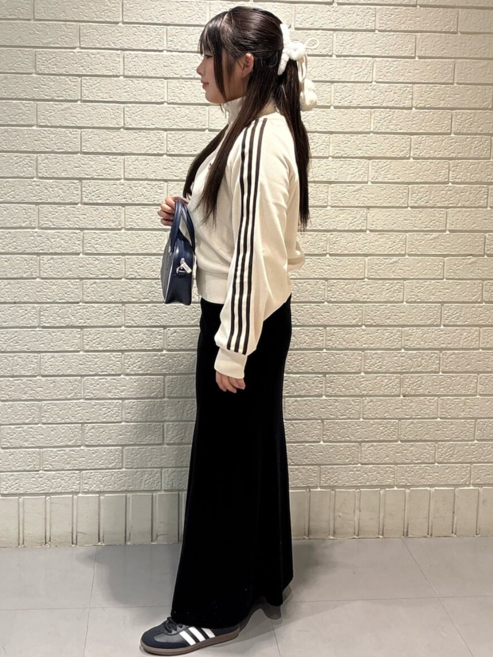 ホワイト系のジャージ、ブルー系のショルダーバッグを着用したレディースの冬コーディネートの2枚目の写真