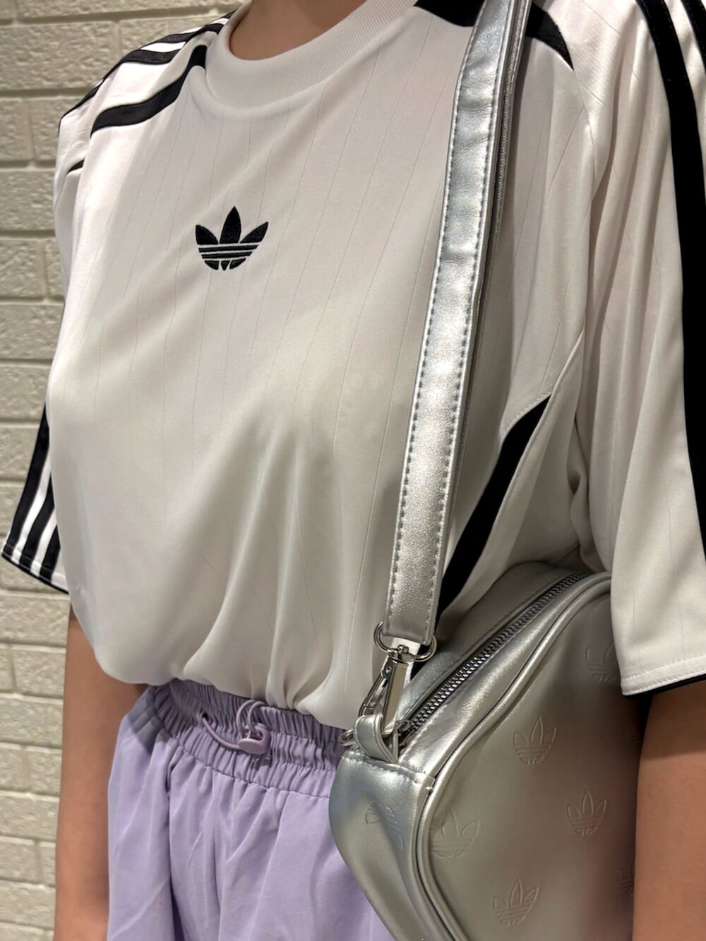 シルバー系のショルダーバッグ、ホワイト系のTシャツ/カットソー、ホワイト系のスニーカーを着用したレディースの夏コーディネートの3枚目の写真