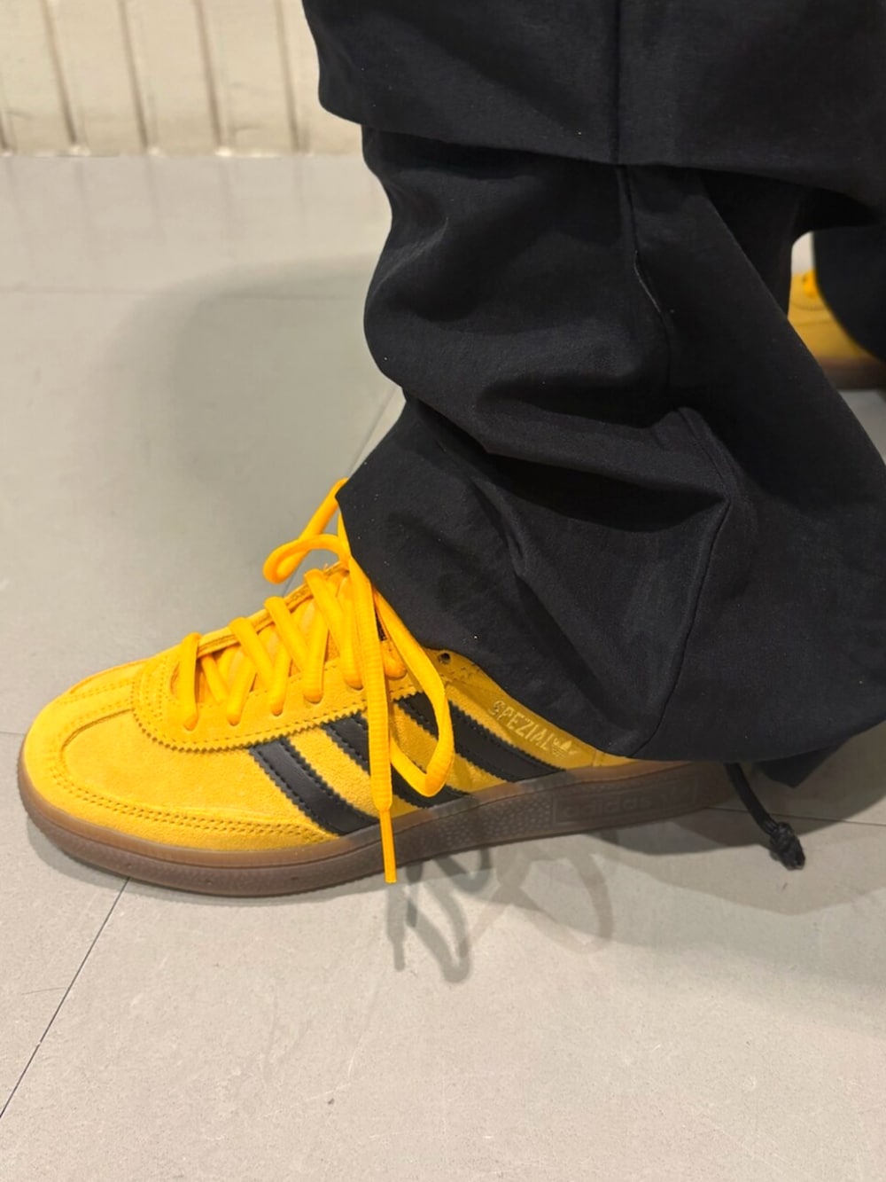 ブラック系のトップス、イエロー系のスニーカーを着用したレディースの秋コーディネートの4枚目の写真