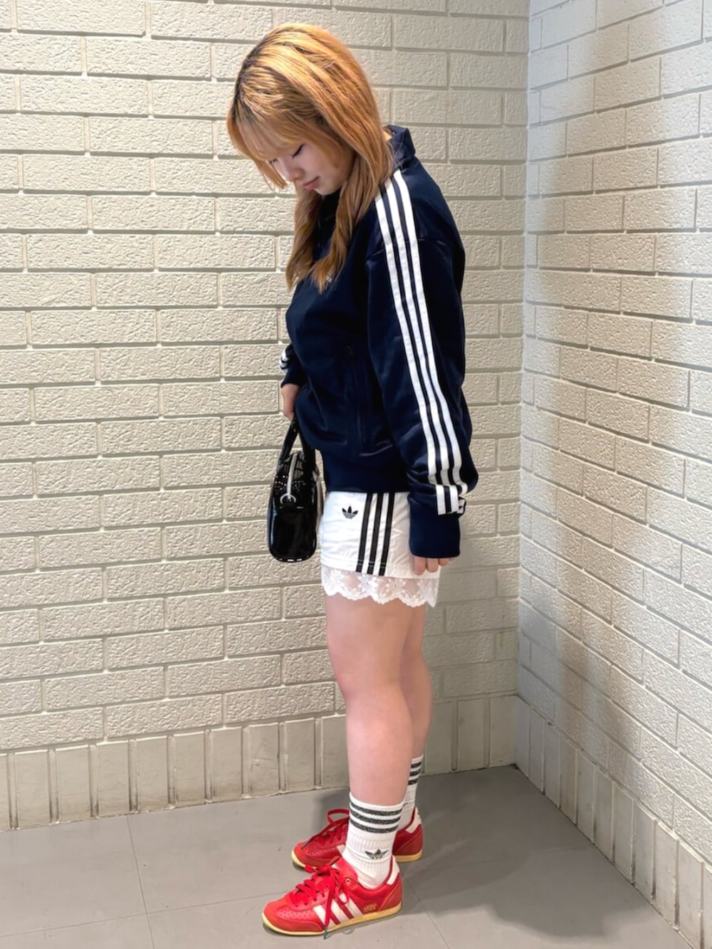 レッド系のスニーカー、ブルー系のジャージ、ホワイト系のその他パンツを着用したレディースの夏コーディネートの2枚目の写真