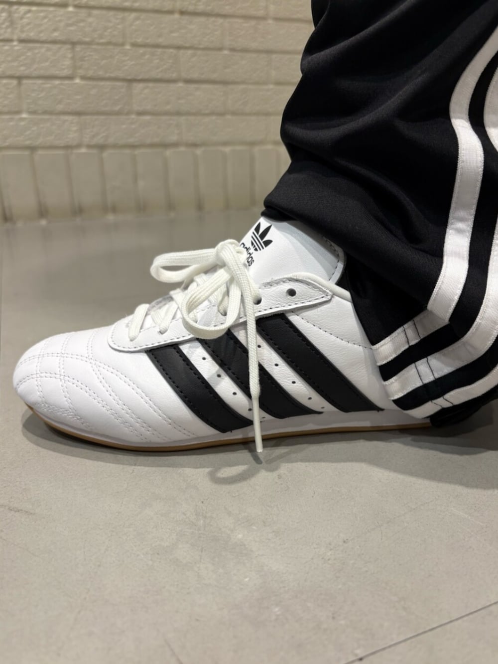 グレー系のナイロンジャケット、ブラック系のスウェットパンツ、ホワイト系のスニーカーを着用したレディースの夏コーディネートの4枚目の写真