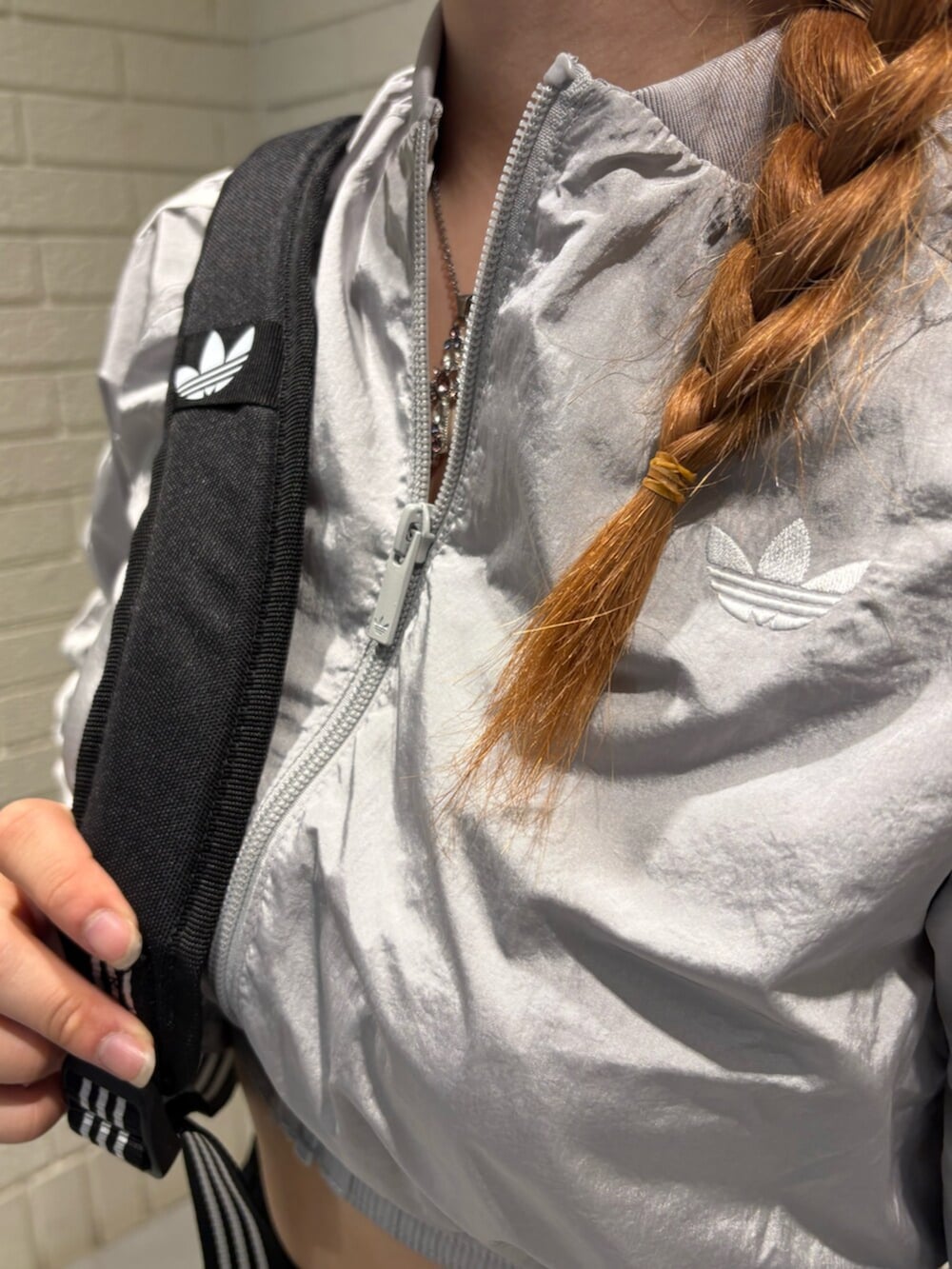 グレー系のナイロンジャケット、ブラック系のスウェットパンツ、ホワイト系のスニーカーを着用したレディースの夏コーディネートの3枚目の写真