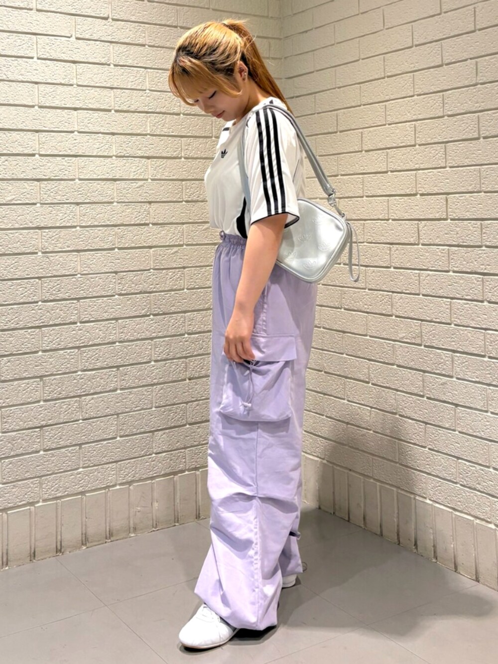 シルバー系のショルダーバッグ、ホワイト系のTシャツ/カットソー、ホワイト系のスニーカーを着用したレディースの夏コーディネートの2枚目の写真