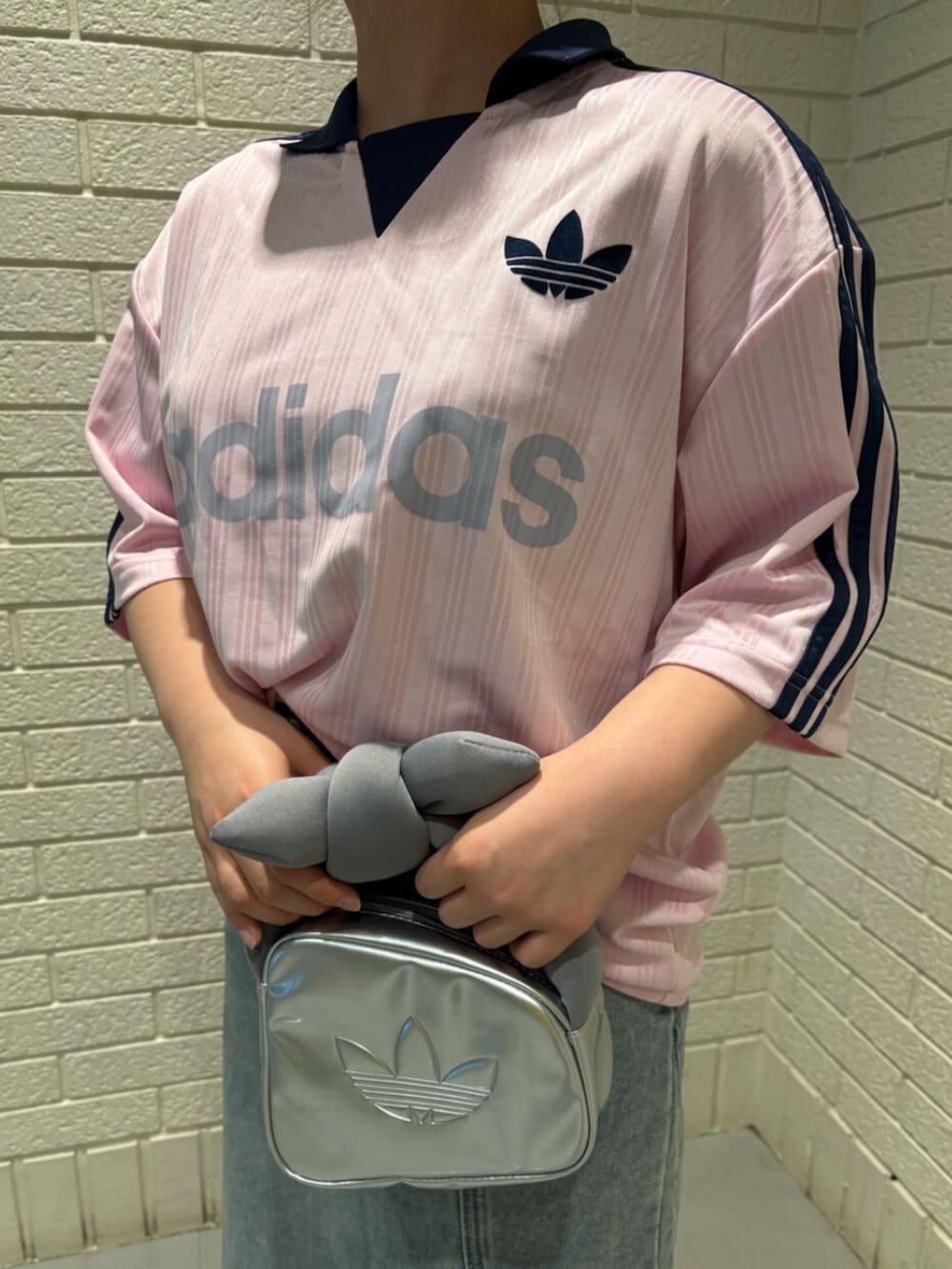 シルバー系のハンドバッグ、ピンク系のスニーカー、ピンク系のトップスを着用したレディースの春コーディネートの3枚目の写真