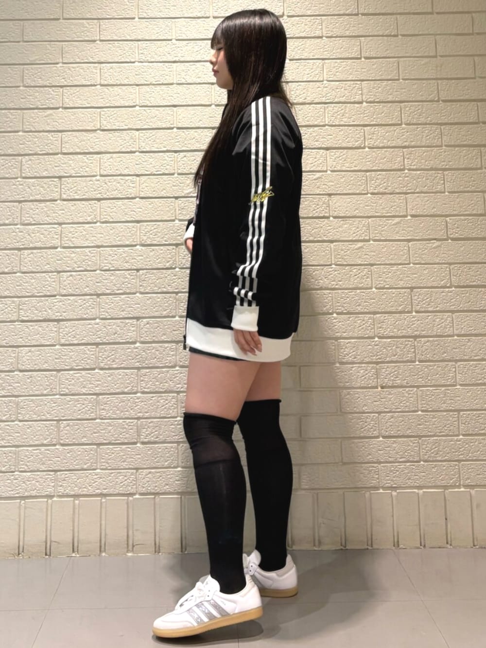 ブラック系のスカート、ホワイト系のスニーカー、ブラック系のジャージを着用したレディースの冬コーディネートの2枚目の写真