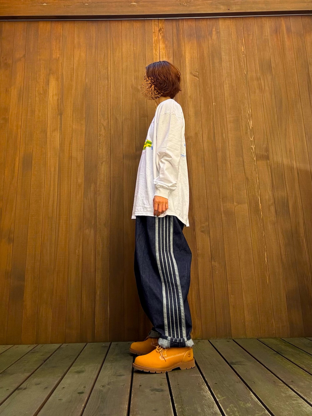 ホワイト系のトップス、ブルー系のデニムパンツ、ベージュ系のスニーカーを着用したレディースの秋コーディネートの2枚目の写真