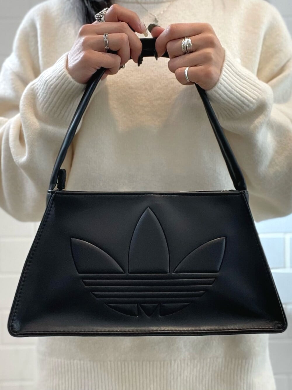 ブラック系のショルダーバッグ、ホワイト系のニット/セーター、ブラック系のスニーカーを着用したレディースの秋コーディネートの4枚目の写真