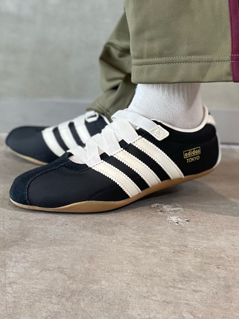 ブラック系のスニーカー、ブラック系のブルゾン、ホワイト系のトップスを着用したレディースの春コーディネートの6枚目の写真