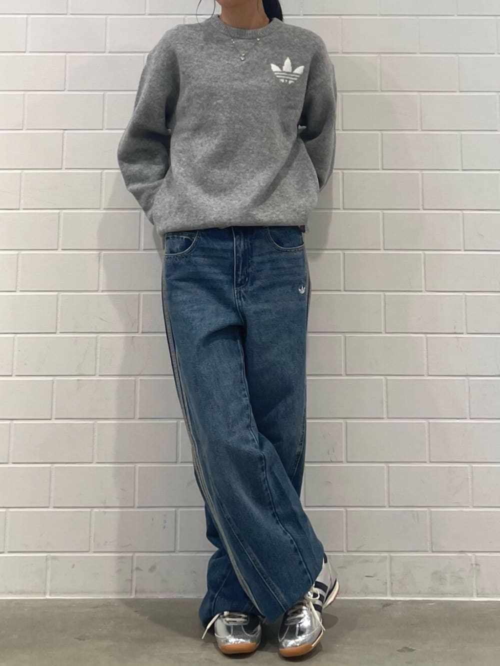 シルバー系のスニーカー、ブルー系のデニムパンツ、グレー系のニット/セーターを着用したレディースの秋コーディネートの2枚目の写真