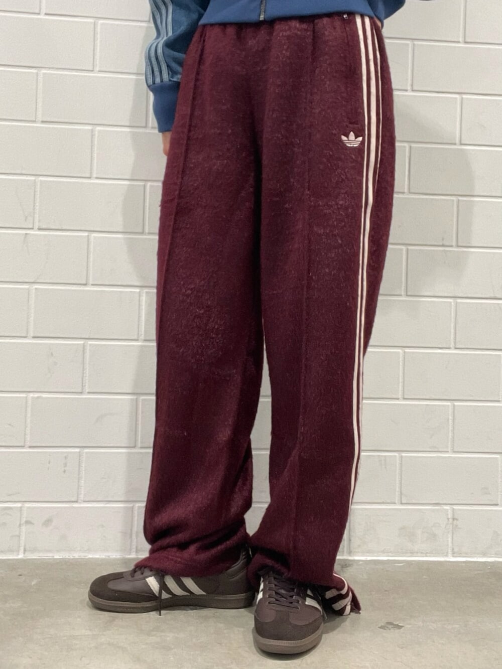 ブルー系のデニムジャケット、ベージュ系のショルダーバッグ、レッド系のスウェットパンツを着用したレディースの秋コーディネートの5枚目の写真