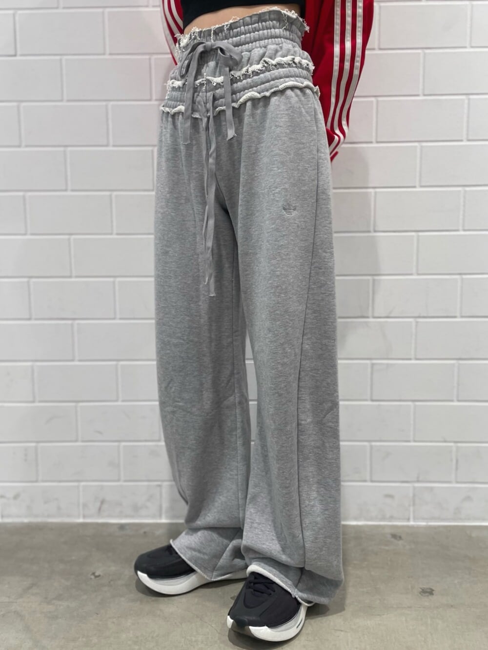 レッド系のジャージ、グレー系のパンツ、ブラック系のスニーカーを着用したレディースの秋コーディネートの5枚目の写真
