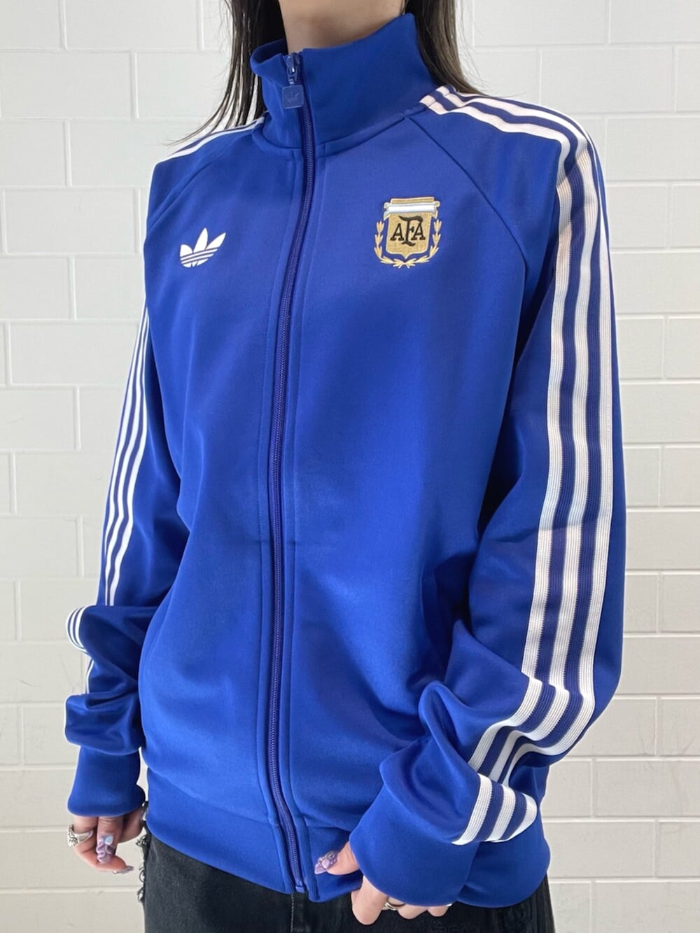 シルバー系のスニーカー、ブラック系のデニムパンツ、ブルー系のジャージを着用したレディースの春コーディネートの4枚目の写真