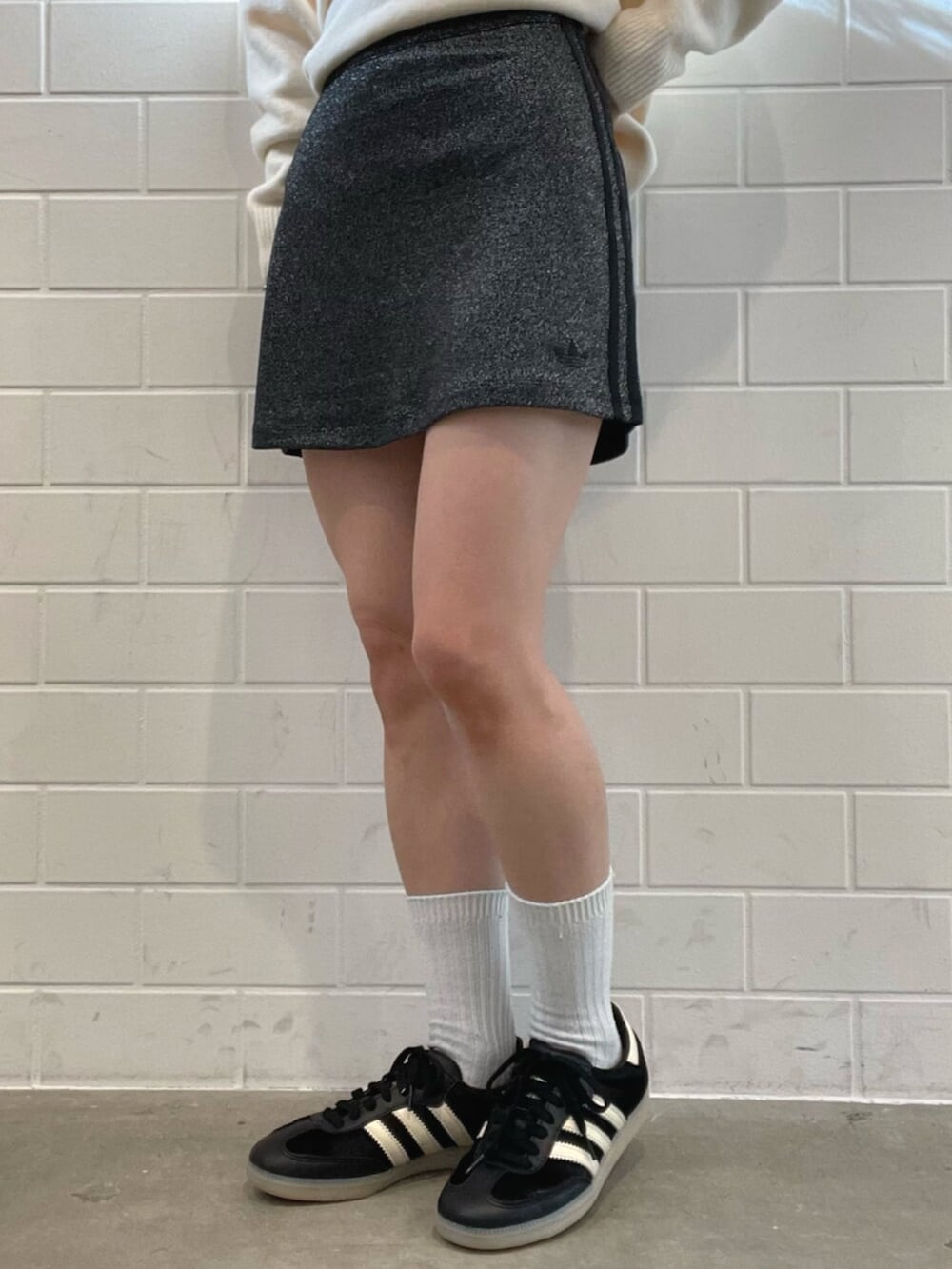 ブラック系のショルダーバッグ、ホワイト系のニット/セーター、ブラック系のスニーカーを着用したレディースの秋コーディネートの5枚目の写真