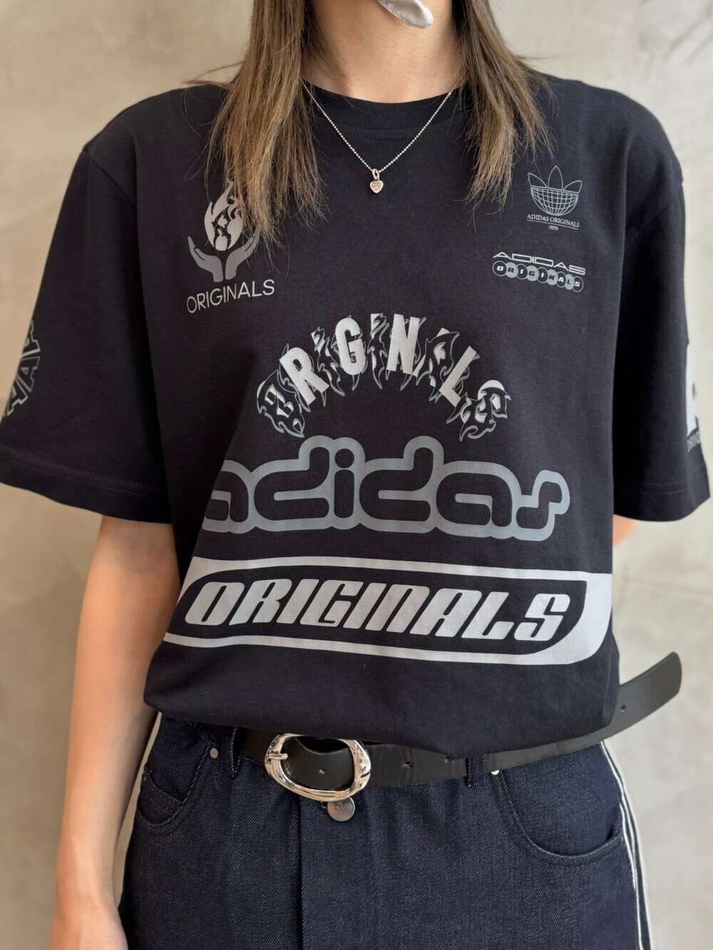 シルバー系のショルダーバッグ、ブラック系のスニーカー、ブラック系のトップスを着用したレディースの夏コーディネートの5枚目の写真