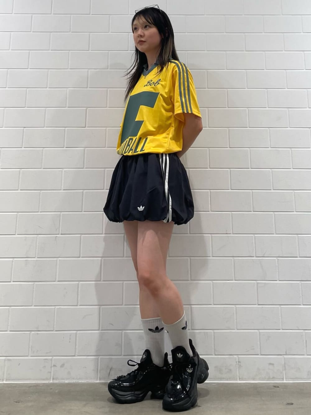 ブラック系のスカート、イエロー系のトップス、ブラック系のスニーカーを着用したレディースの冬コーディネートの3枚目の写真