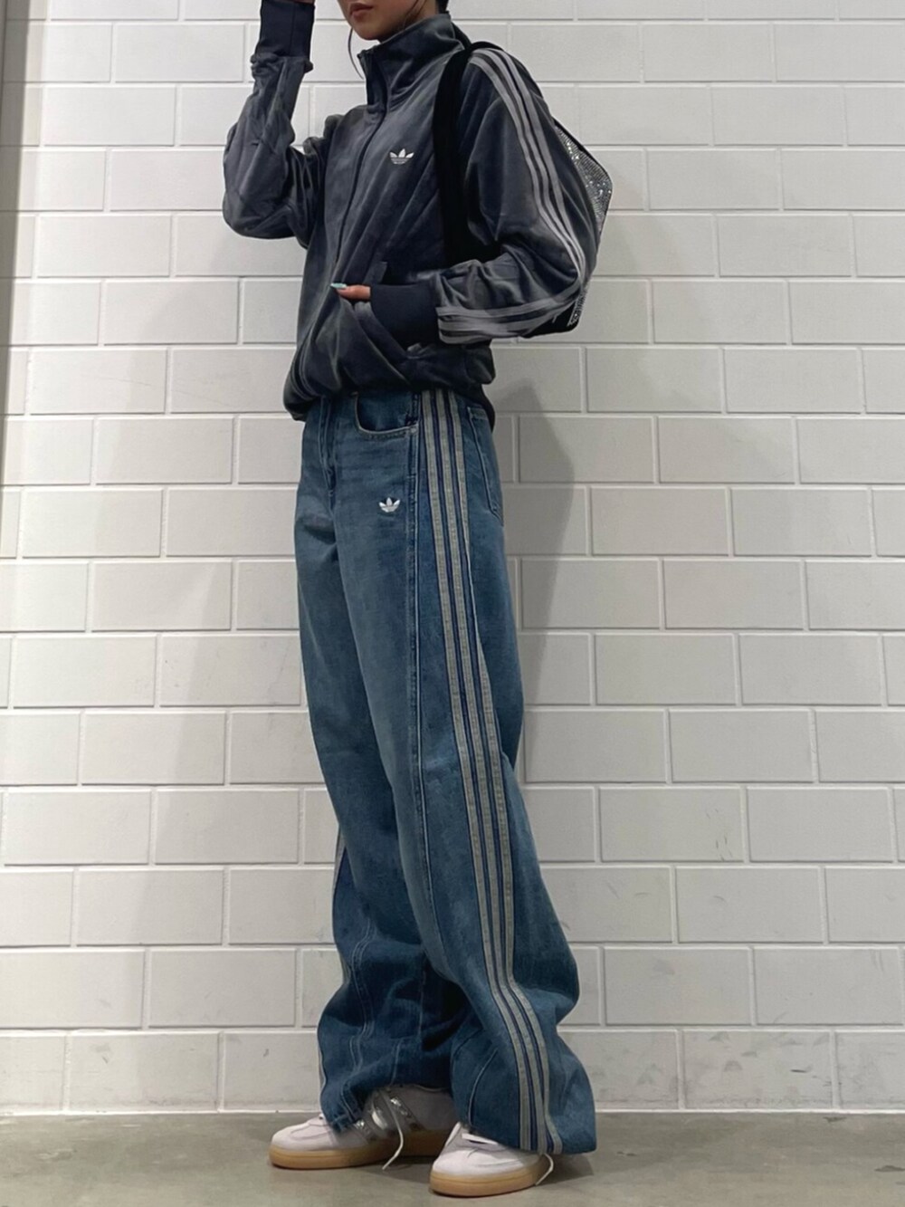 ブラック系のショルダーバッグ、グレー系のスニーカー、ブルー系のパンツを着用したレディースの秋コーディネートの2枚目の写真