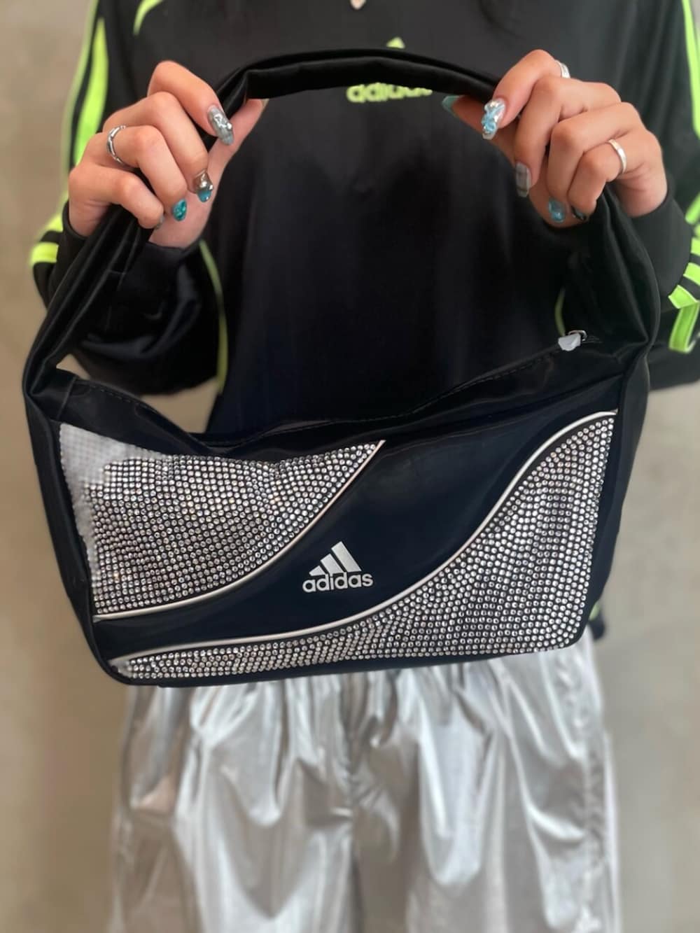 ブラック系のスニーカー、ブラック系のショルダーバッグ、シルバー系のスウェットパンツを着用したレディースの秋コーディネートの4枚目の写真