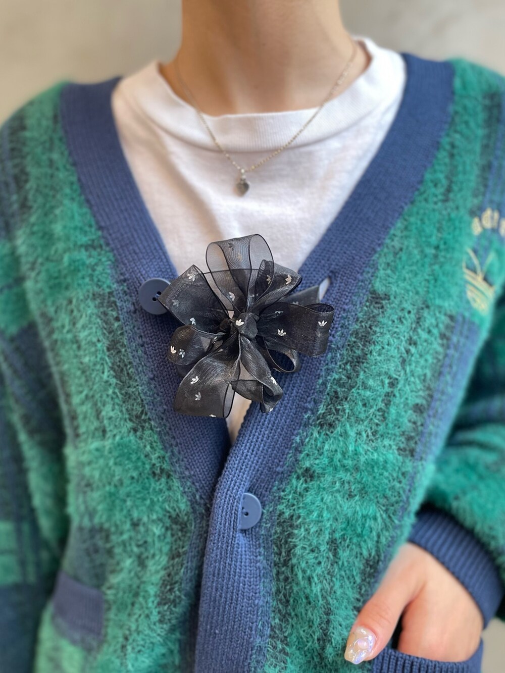 グリーン系のカーディガン/ボレロ、ブラック系のシューズアクセサリー、ブラック系のショルダーバッグを着用したレディースの秋コーディネートの4枚目の写真