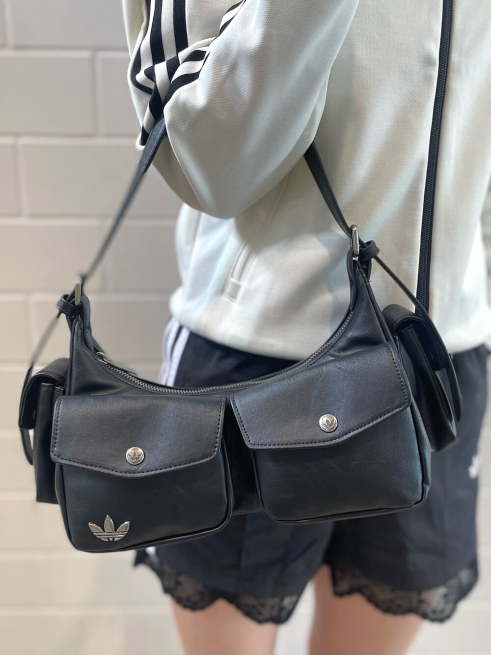 ブラック系のショルダーバッグ、ブラック系のスニーカー、ホワイト系のトップスを着用したレディースの春コーディネートの4枚目の写真