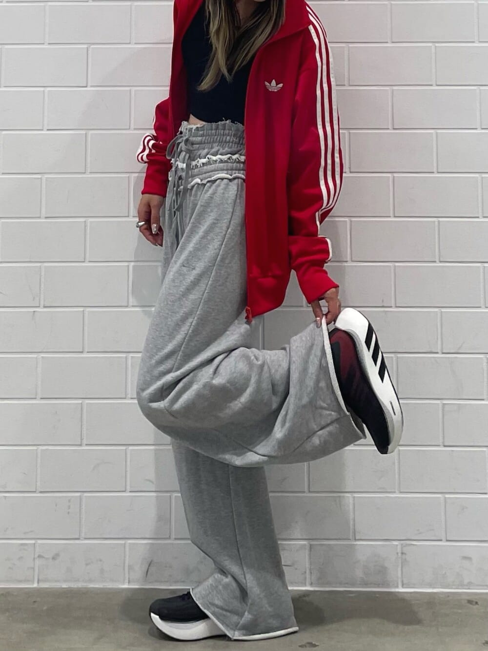 レッド系のジャージ、グレー系のパンツ、ブラック系のスニーカーを着用したレディースの秋コーディネートの2枚目の写真