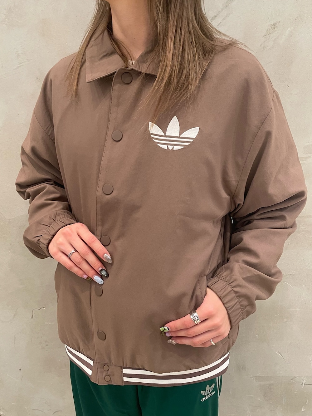 ブラウン系のジャケット/アウター、ホワイト系のニット/セーター、グレー系のスニーカーを着用したレディースの冬コーディネートの4枚目の写真