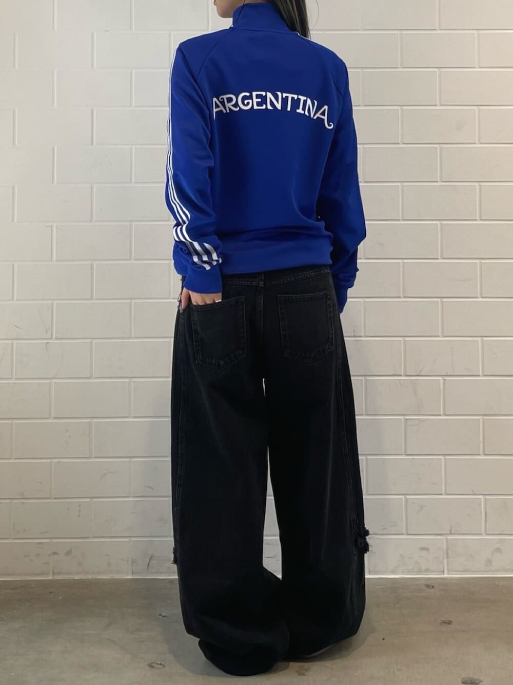 シルバー系のスニーカー、ブラック系のデニムパンツ、ブルー系のジャージを着用したレディースの春コーディネートの2枚目の写真