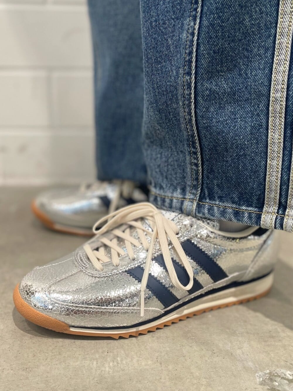 シルバー系のスニーカー、ブルー系のデニムパンツ、グレー系のニット/セーターを着用したレディースの秋コーディネートの6枚目の写真