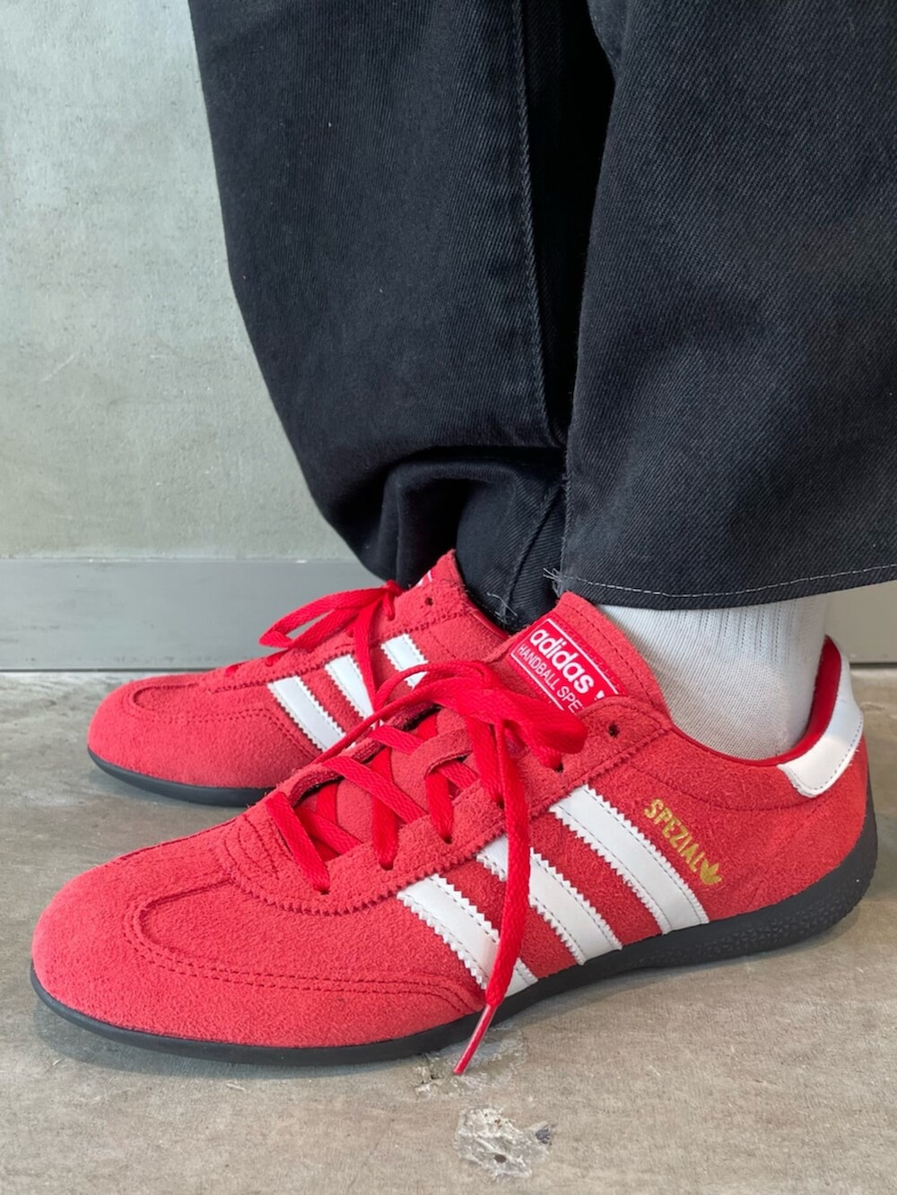 レッド系のスニーカー、ブラック系のトップス、ブラック系のハットを着用したレディースの春コーディネートの6枚目の写真