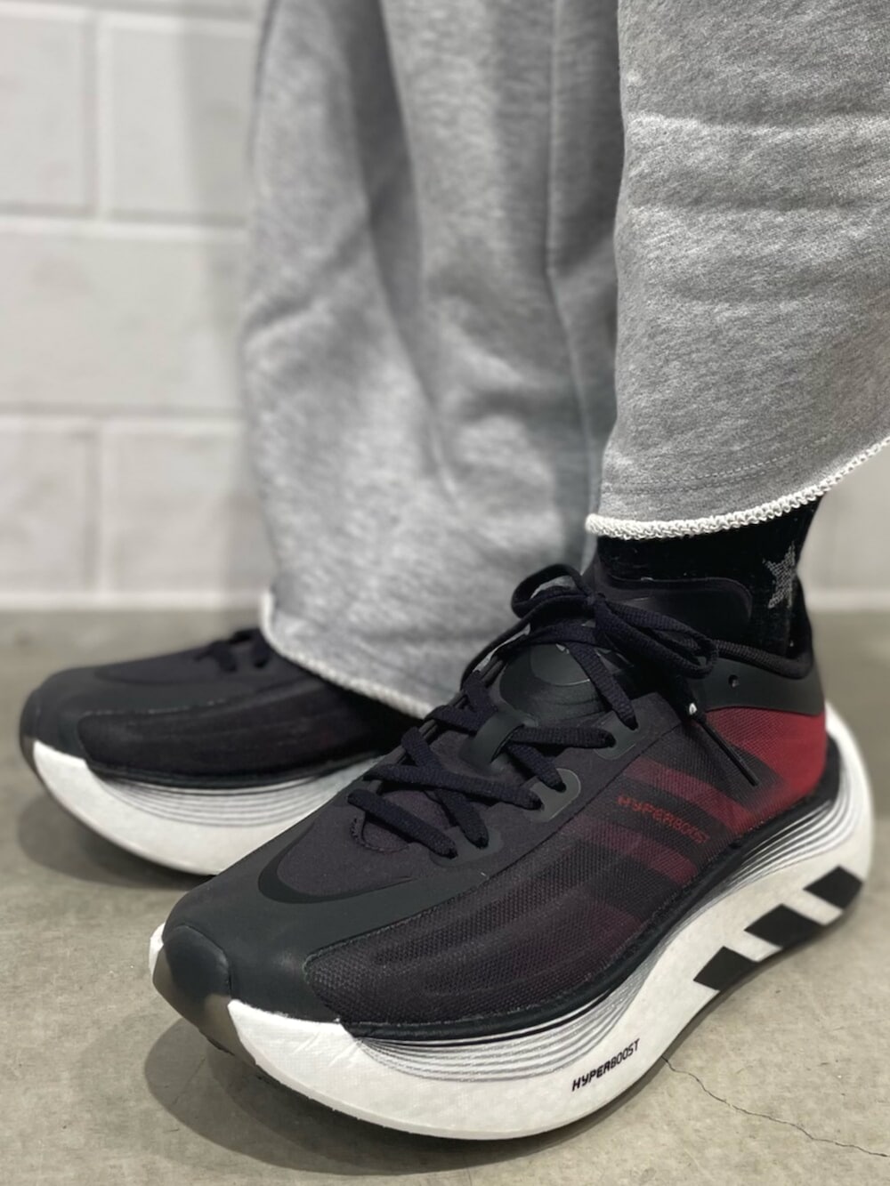 レッド系のジャージ、グレー系のパンツ、ブラック系のスニーカーを着用したレディースの秋コーディネートの6枚目の写真