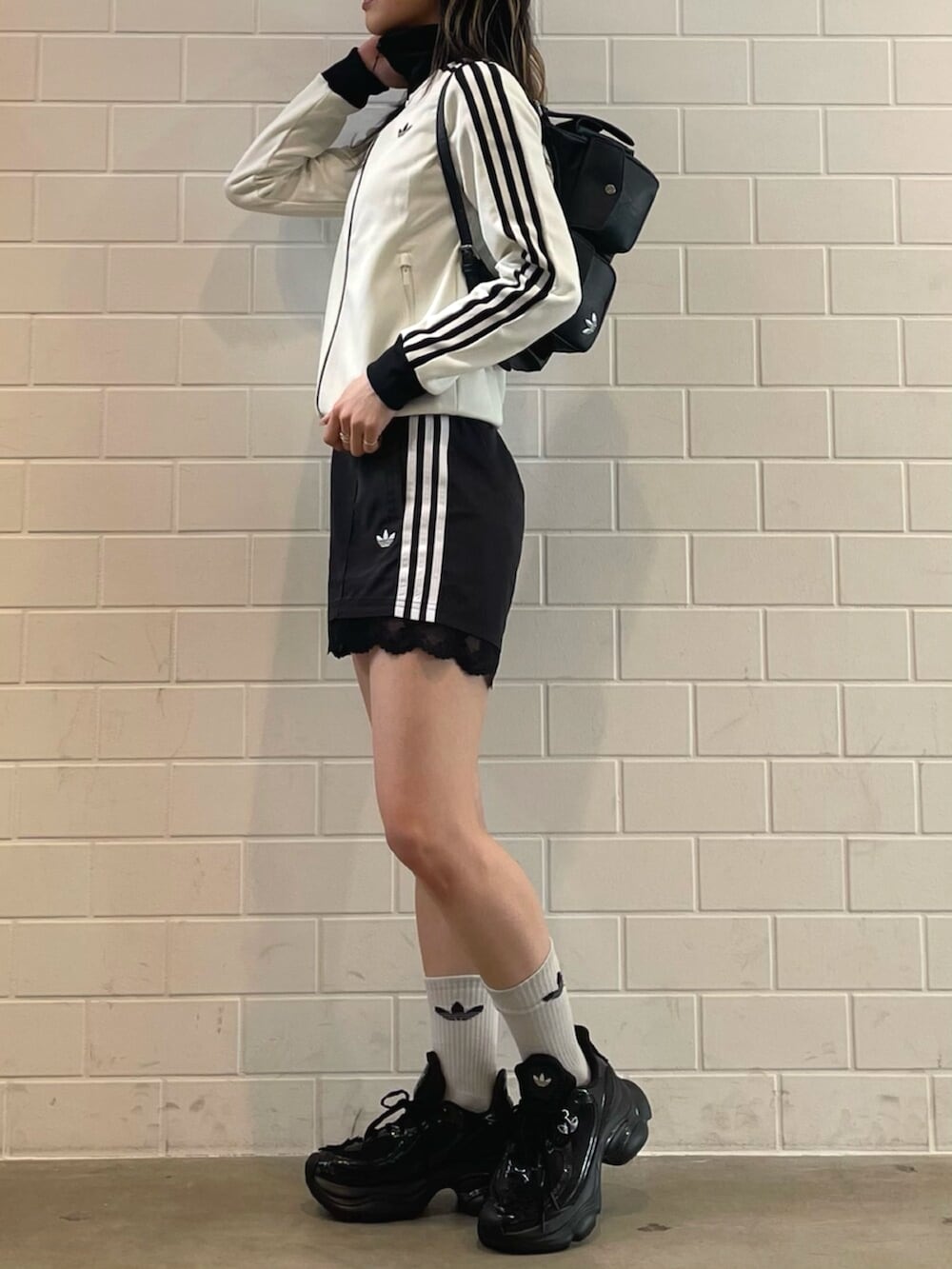 ブラック系のショルダーバッグ、ブラック系のスニーカー、ホワイト系のトップスを着用したレディースの春コーディネートの2枚目の写真