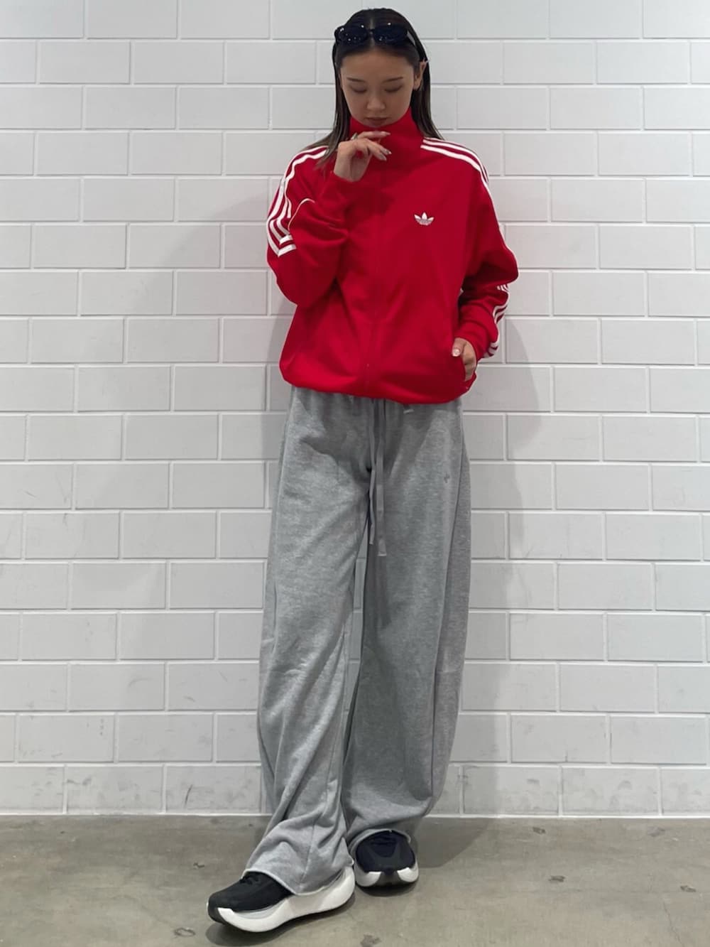 レッド系のジャージ、グレー系のパンツ、ブラック系のスニーカーを着用したレディースの秋コーディネートの3枚目の写真