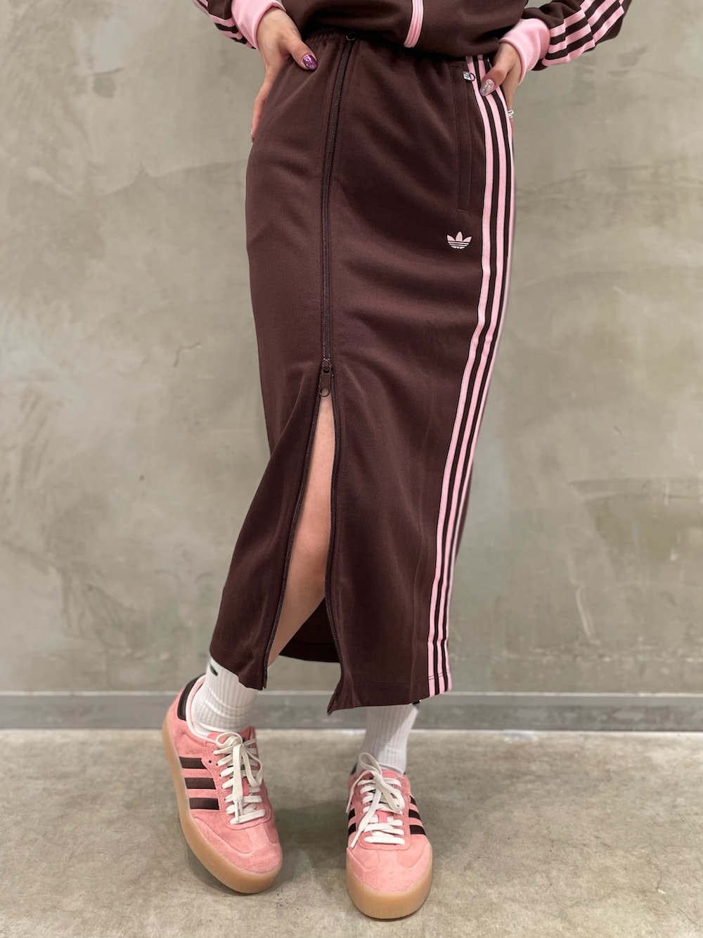 ピンク系のスニーカー、ブラウン系のスカート、ブラウン系のジャージを着用したレディースの秋コーディネートの4枚目の写真