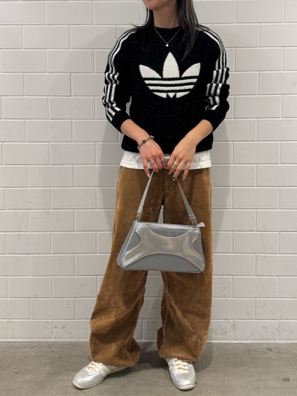 シルバー系のショルダーバッグ、ブラック系のスウェット、ブラウン系のその他パンツを着用したレディースの秋コーディネートの2枚目の写真