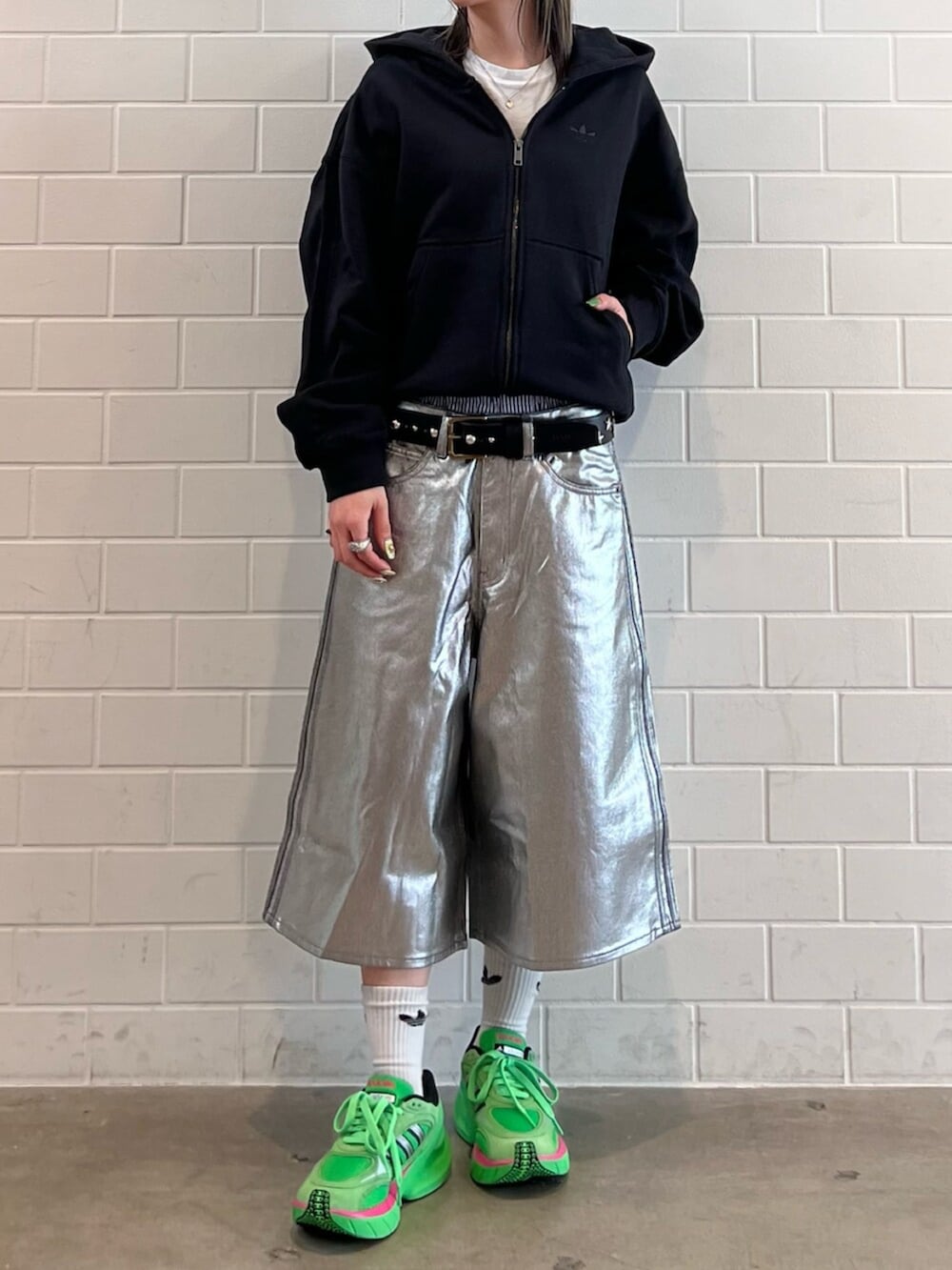 ブラック系のパーカー、グリーン系のシューズ、シルバー系のデニムパンツを着用したレディースの冬コーディネートの2枚目の写真