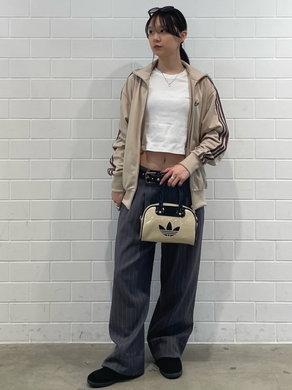 ブラック系のスニーカー、ベージュ系のトップス、ベージュ系のショルダーバッグを着用したレディースの春コーディネートの3枚目の写真