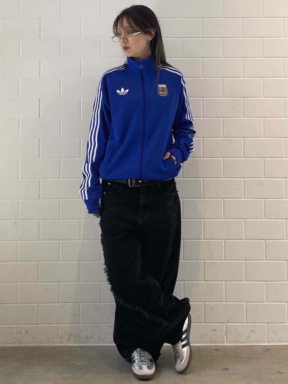 シルバー系のスニーカー、ブラック系のデニムパンツ、ブルー系のジャージを着用したレディースの春コーディネートの3枚目の写真