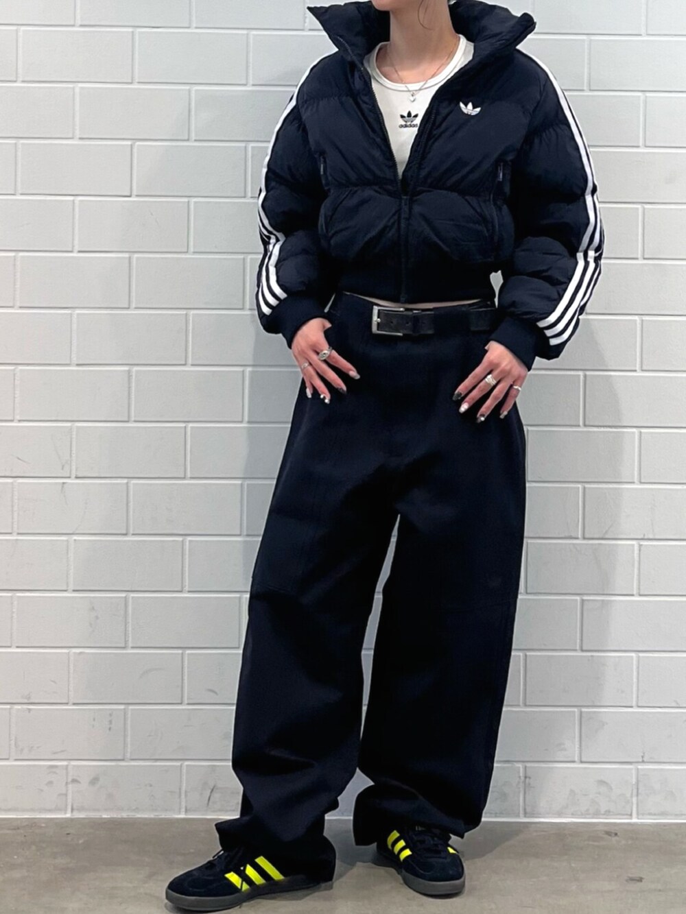 ホワイト系のTシャツ/カットソー、ブラック系のスニーカー、ブラック系のダウンジャケット/コートを着用したレディースの秋コーディネートの2枚目の写真