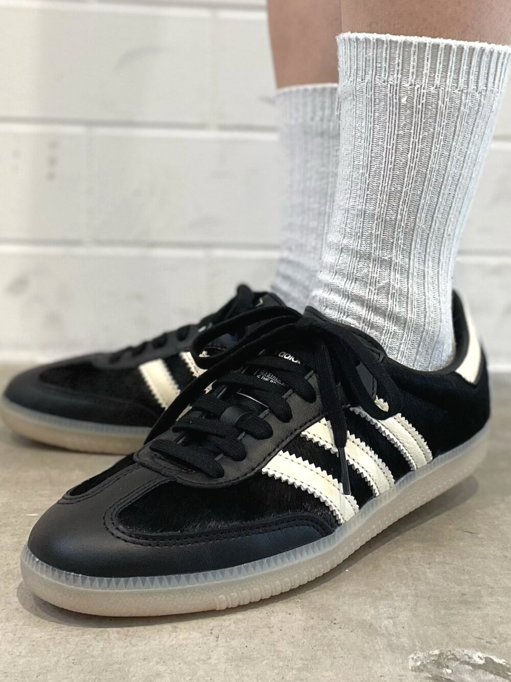 ブラック系のショルダーバッグ、ホワイト系のニット/セーター、ブラック系のスニーカーを着用したレディースの秋コーディネートの6枚目の写真