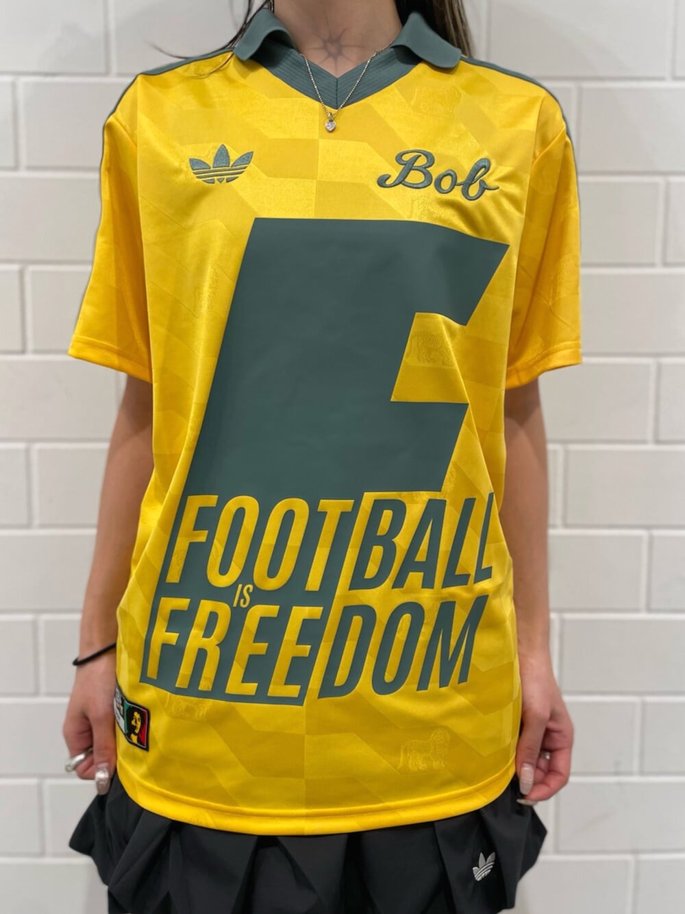 ブラック系のスカート、イエロー系のトップス、ブラック系のスニーカーを着用したレディースの冬コーディネートの4枚目の写真