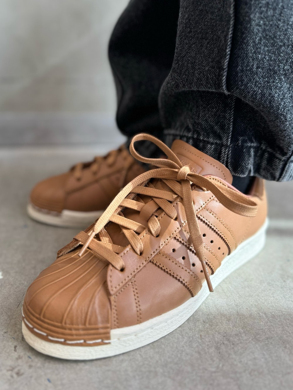 ブラック系のベスト、オレンジ系のパーカー、ブラック系のデニムパンツを着用したレディースの秋コーディネートの6枚目の写真