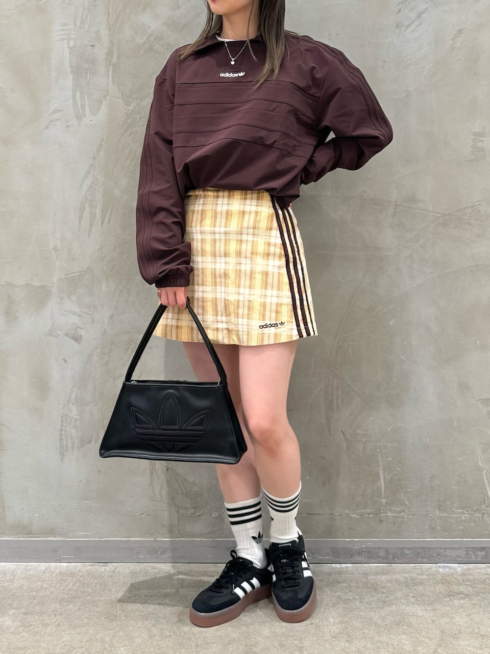 ブラウン系のTシャツ/カットソー、ベージュ系のスカート、ブラック系のショルダーバッグを着用したレディースの秋コーディネートの2枚目の写真