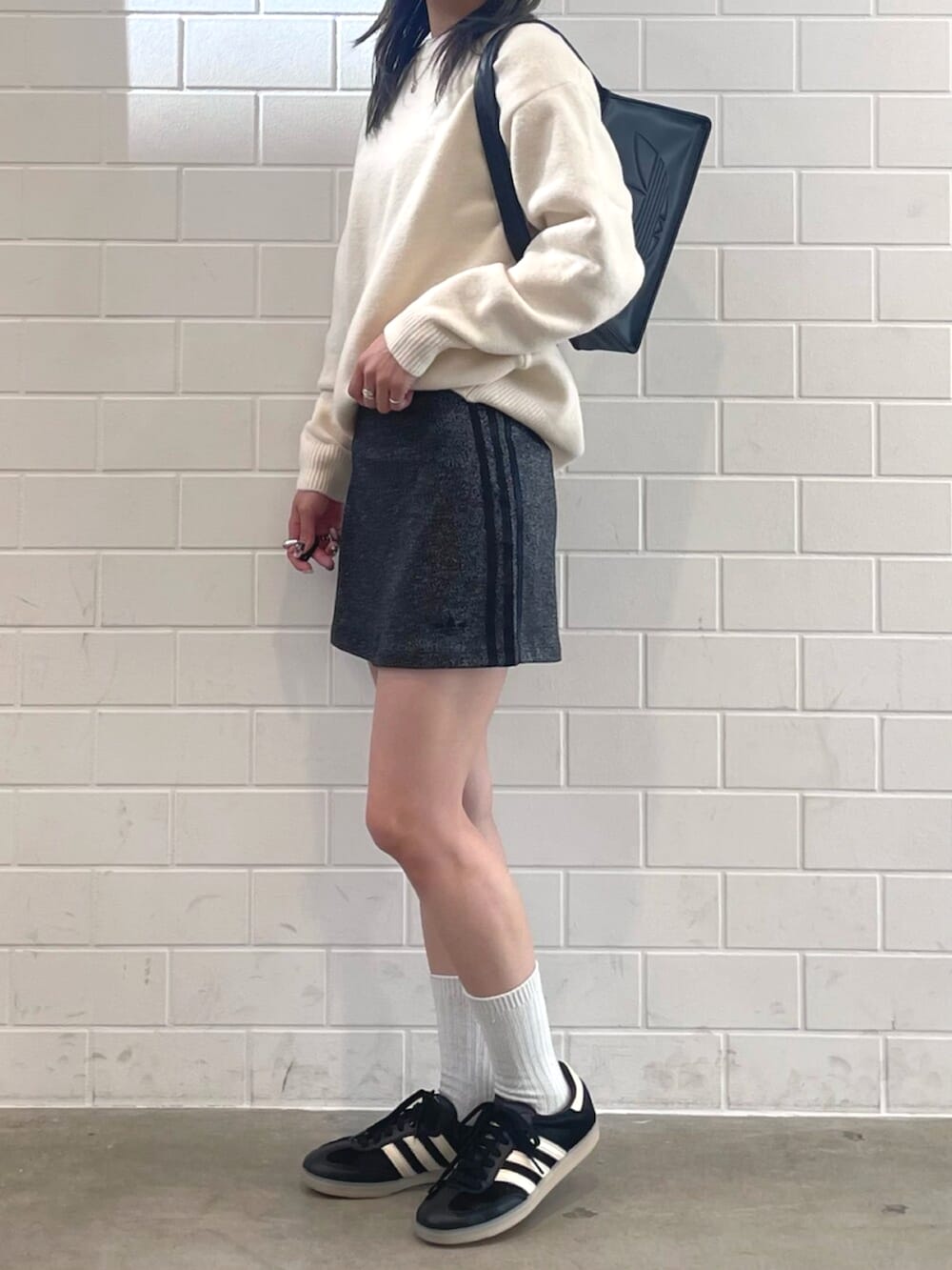 ブラック系のショルダーバッグ、ホワイト系のニット/セーター、ブラック系のスニーカーを着用したレディースの秋コーディネートの2枚目の写真