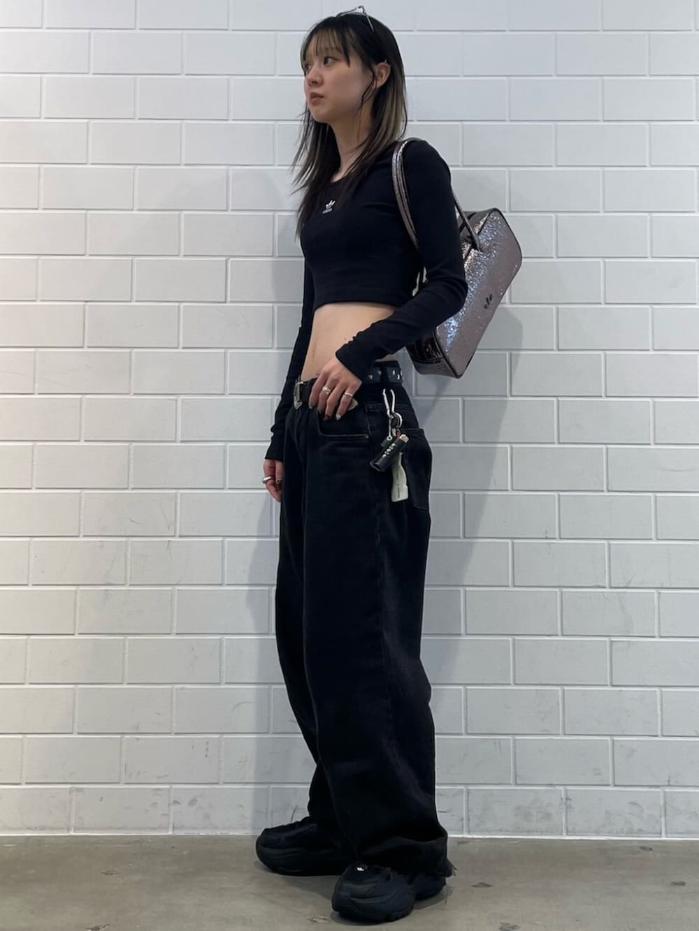 ブラック系のスニーカー、ブラック系のTシャツ/カットソー、グレー系のショルダーバッグを着用したレディースの冬コーディネートの3枚目の写真