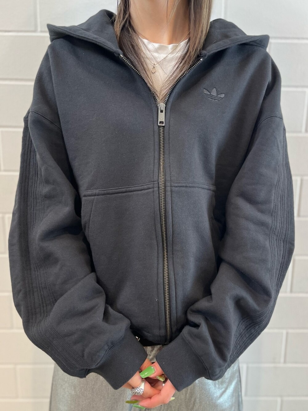 ブラック系のパーカー、グリーン系のシューズ、シルバー系のデニムパンツを着用したレディースの冬コーディネートの4枚目の写真