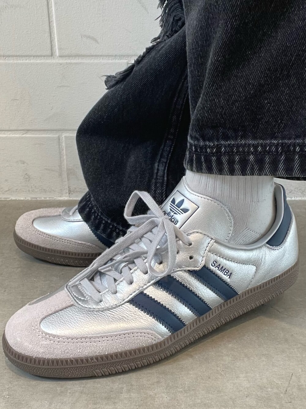 シルバー系のスニーカー、ブラック系のデニムパンツ、ブルー系のジャージを着用したレディースの春コーディネートの6枚目の写真