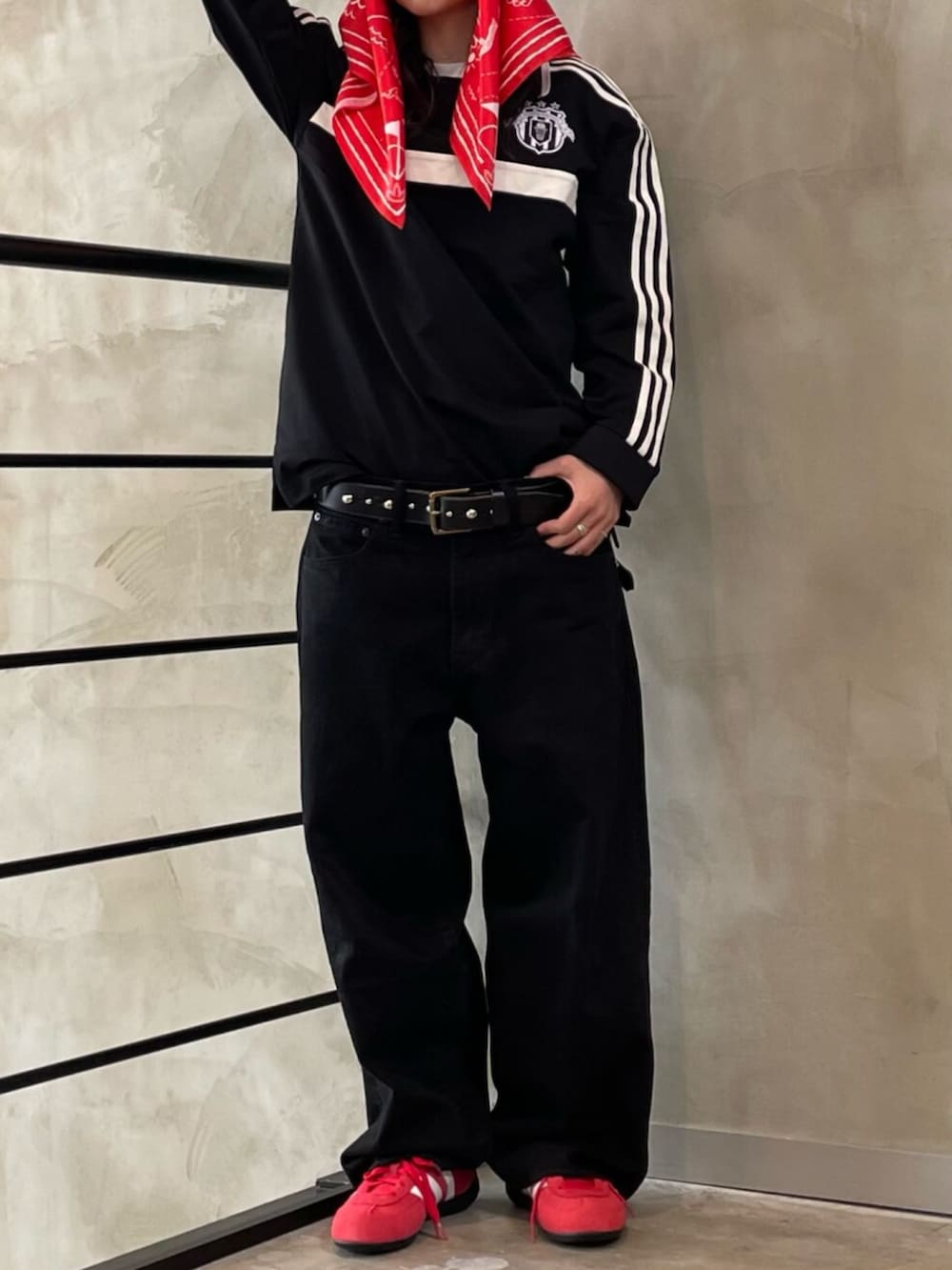 レッド系のスニーカー、ブラック系のトップス、ブラック系のハットを着用したレディースの春コーディネートの2枚目の写真