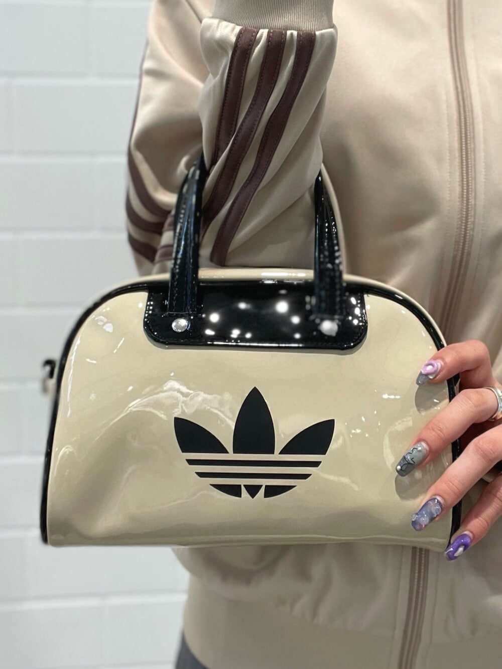 ブラック系のスニーカー、ベージュ系のトップス、ベージュ系のショルダーバッグを着用したレディースの春コーディネートの5枚目の写真