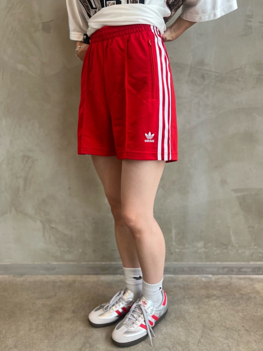 シルバー系のシューズ、ホワイト系のトップス、レッド系のパンツを着用したレディースの夏コーディネートの5枚目の写真